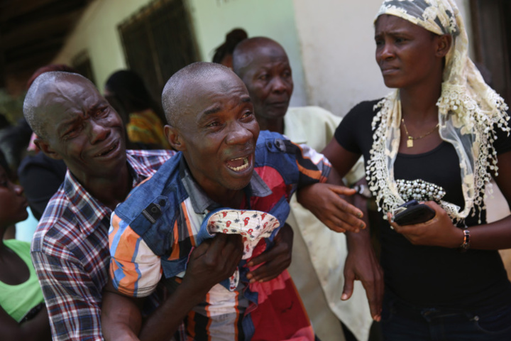 Cet homme pleure de toutes ses larmes à la vue de l'équipe de sépulture Ebola venue récupérer le corps de sa femme pour la crémation (John Moore / Getty Images)