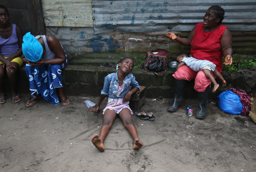 Sophia Doe (R), et ses petites-filles Arthuneh Qunoh (C), 9 et Beauté Mandi, 9 mois (2e R) en pleurs à l’arrivée d'une équipe de sépulture Ebola, qui est venue récupérer la dépouille de sa sœur morte d'Ebola, pour la crémation, le 10 Octobre 2014 à Monrovia, au Libéria. (John Moore / Getty Images)
