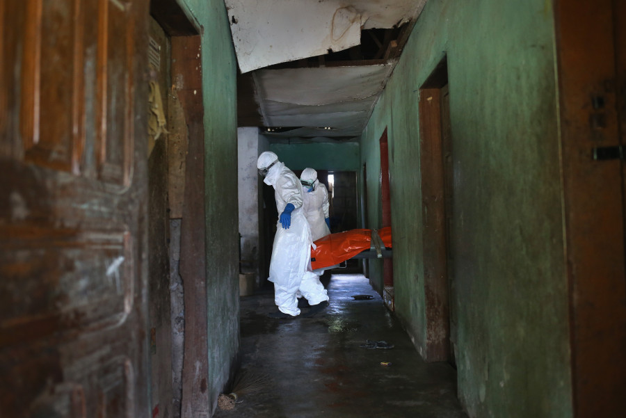 Une équipe de sépulture Ebola, vêtue de vêtements de protection, porte le corps d'une femme, 54 ans, de la chambre où elle est décédée dans la banlieue de New Kru ville le 10 Octobre 2014 à Monrovia, au Libéria. (John Moore / Getty Images)