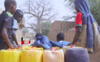 Des enfants transportent des bidons d'eau remplis dans un village riverain.